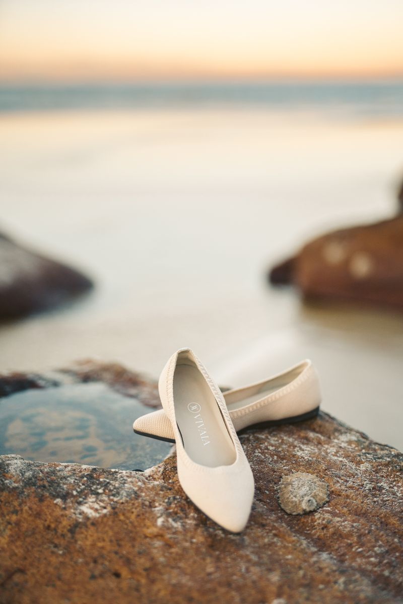 Cream pointed-toe flats on brown stone